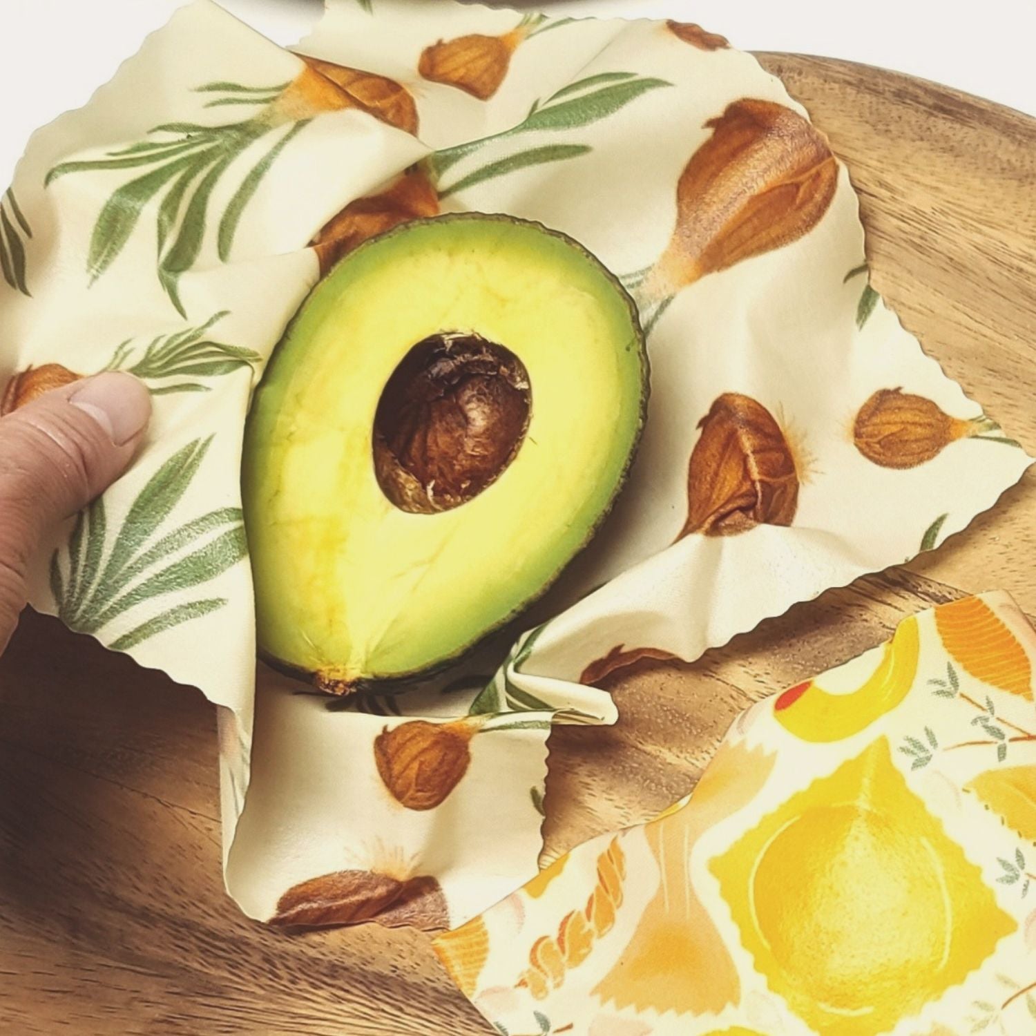 Half-cut avocado on a reusable food wrap with a fruit pattern