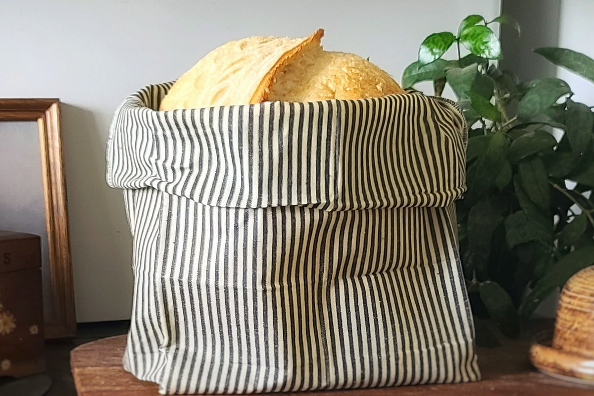 linen bread bag with indigo stripes holding sourdough bread