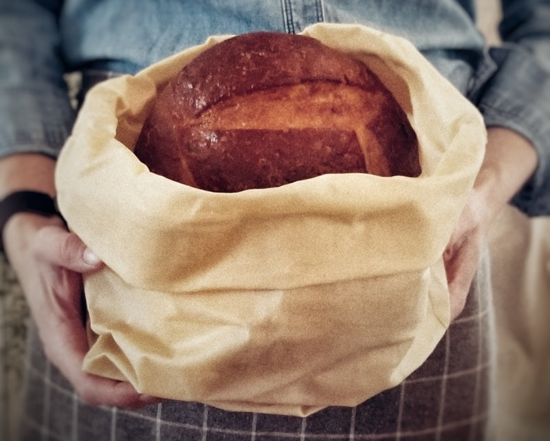 Loaf of bread wrapped in a beeswax bag held by a person